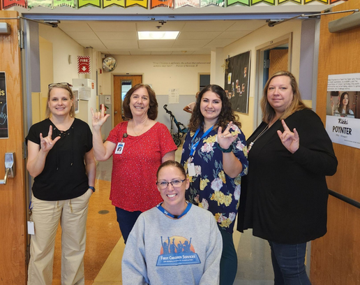 A group of teachers holding up their hands to show sign language.