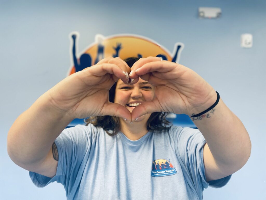 An FCS staff member holding up a heart with her hands